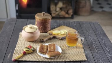 Doldurulmuş gözleme ve ahşap bir masada limonlu çay yanan bir şömine ve odun sobasının arka planına karşı, kırsal tarzda yiyeceklerle dolu sakin bir hayat.
