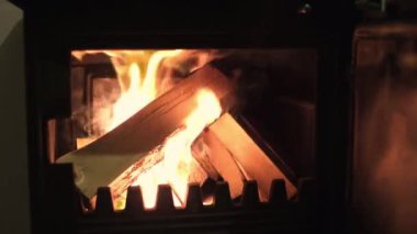 Şöminenin içinde bir odun ateşi yanıyor. Cam bir örtünün arkasındaki evde.