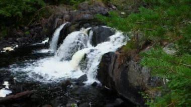 Nehir dağ manzarası arasında akar, dağlık bir nehirde küçük bir şelale, seçici bir odak noktası.