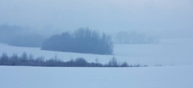 Kış sabahı manzarası. Şafak Alan karla, bulutlarla ve uzaktaki odunlarla kaplıydı. Sıra dışı mavi bir sis vardı. Gökyüzü ve yeryüzü tek bir bütün halinde birleşti..