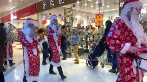 Algunas Santa Claus están caminando por el centro comercial y tocando instrumentos musicales. — Vídeo de stock