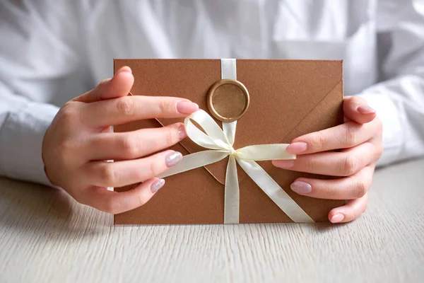 close-up photo of invitation envelope with ribbon and wax seal, gift certificate, wedding invitation card