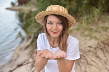 Kız kameraya bakıyor ve iki avuç içi açık öpücük yolluyor. Kadın gülüyor ve ormanda ya da parkta yürürken mutlu oluyor ve sevgilisine video çağrısı yapıyor.