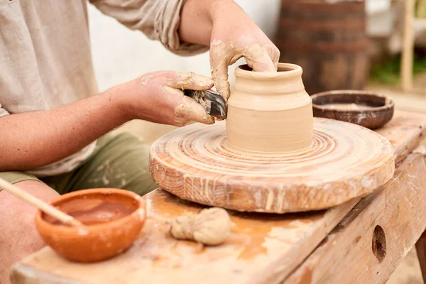 male craftsman sculpts jug or vase from clay