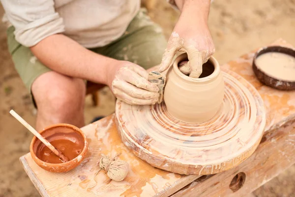 man makes clay product on mechanical potter\'s wheel