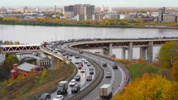 Auta jedou pomalu po silnici ve městě, dopravní zácpa na mostě přes řeku. Podzim. Žluté stromy — Stock video
