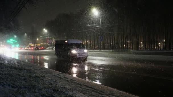 Straat. Auto 's rijden' s avonds op de weg tijdens een sneeuwval, een sneeuwstorm — Stockvideo