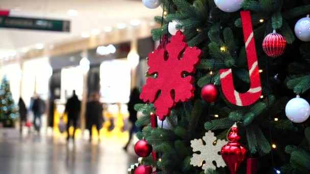 En julgran med leksaker, snöflingor och krans installeras i ett köpcentrum, folk går förbi. Julen — Stockvideo