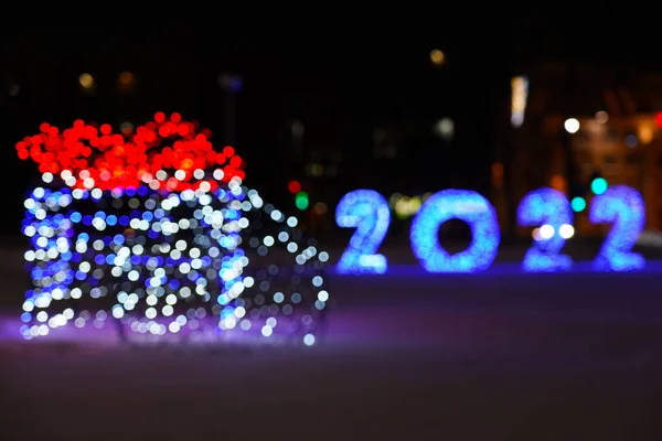 The inscription of the numbers 2022 is blue on the background of a garland in the form of a gift