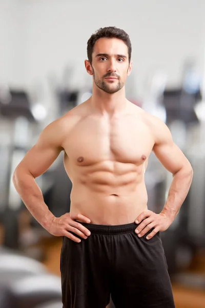 Passar man står med armarna på hans midja i ett gym — Stock fotografie
