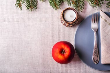 Noel 'de gri tabak, çatal, gri peçete, mum, kırmızı elma ve köknar ağacı servis edilir. Kopyalama alanı olan üst görünüm