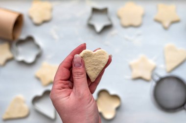 Kadın elleri kalp, yıldız, bulut ve çiçek şeklinde zencefilli kurabiye pişiriyor. Noel ve Yeni Yıl konsepti, kış köylüleri için şenlikli hazırlıklar
