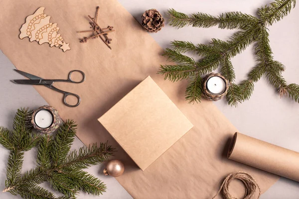 Verpackung eines Geschenks für Weihnachten und Neujahr aus umweltfreundlichen Materialien: Kraftpapier, lebende Tannenzweige, Zapfen, Bindfäden. Stichworte mit Attrappe, natürliches Dekor, handgefertigt, Flatlay. — Stockfoto