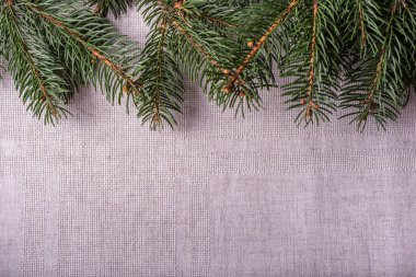 Gri keten masa örtüsü arka planında doğal ladin kozalaklı yeşil dallar. Noel masasının şenlikli dekorasyonu. Üst Manzara. Boşluğu kopyala.