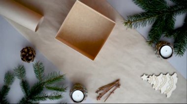 Kadınların elleri, Noel için yeni yıl hediyelerini çevre dostu malzemelerle paketliyor. Kurdele kurdelesiyle bağlanmış el işi kağıt kutu..