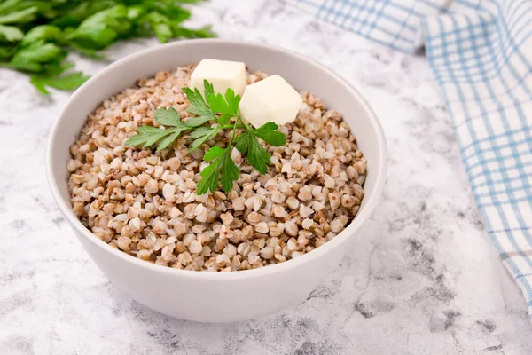Gri arka planda bir tabakta taze pişmiş karabuğday lapası. Sağlıklı yiyecekler. Vejetaryen yemeği..