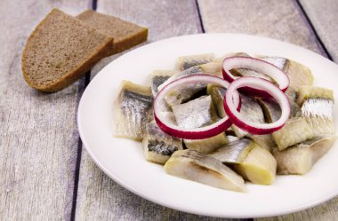 Salamura edilmiş ringa balığı, dilimlenmiş balık filetosu ve masada doğranmış soğan halkaları.