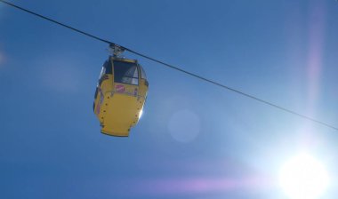 Avustralya 'da kış sporlarında kayak pistlerinin üzerinde, mavi güneşli gökyüzünün altında kar ve ağaçlarla dolu sarı bir sandalye.