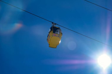 Sarı kayak kamaraları kar ve ağaçlarla kaplı mavi güneşli gökyüzünün altında kış sporu dağlarındaki kayak yamaçlarının üstünde.
