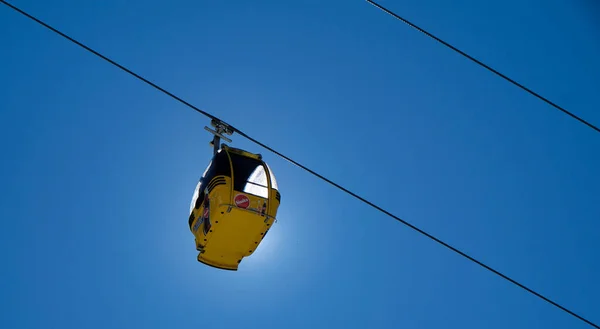 Cabines de elevação de esqui amarelas com neve e árvores sob o céu azul ensolarado acima das pistas de esqui nas montanhas de inverno — Fotografia de Stock