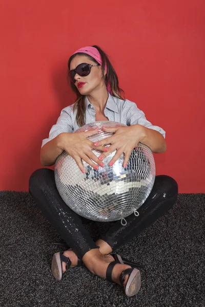 Jovem mulher com bola de discoteca Sobre fundo vermelho — Fotografia de Stock