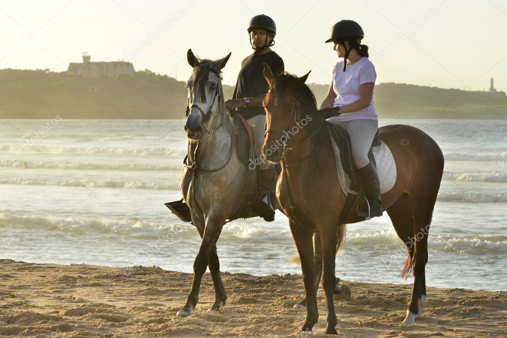 Young men and her horse gallop along the beach