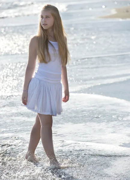 Jeune femme en robe blanche marchant sur la plage. — Photo