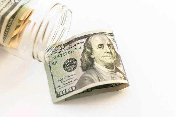 İçinde Amerikan parası olan cam kavanoz ve beyaz arka planda 100 dolar, üst manzara, düz yatak. Para ve finans.