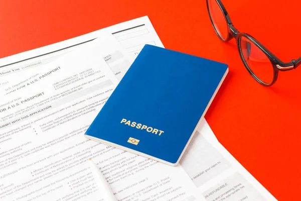 21 Eylül 2021, ABD. Yeni bir Amerikan pasaportu için başvuru formu, kırmızı kalem, kırmızı arka planda gözlük. ABD belgesi. İş teması. Seçici odak.