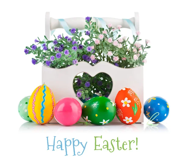 Easter eggs in wooden basket with spring flowers — Stock Photo, Image