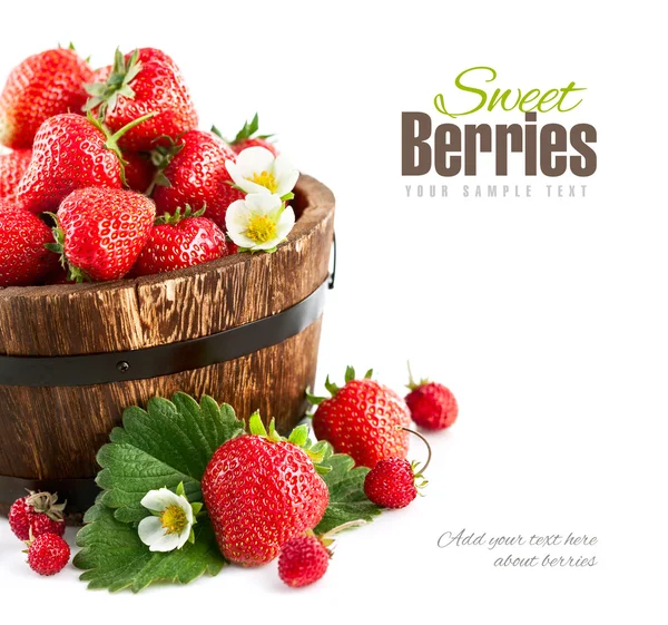 Frische Erdbeeren in hölzerner Eimer mit grünen Blättern und Blumen — Stockfoto