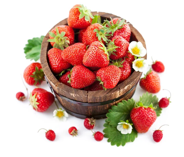 Frische Erdbeeren in hölzerner Eimer mit grünen Blättern und Blumen — Stockfoto