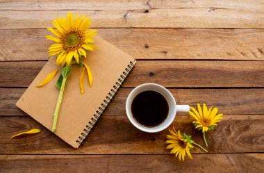 Sıcak kahveyle dizüstü bilgisayar planlayıcısı, ayçiçeği düzenleme düz arka plan ahşap üzerine uzanma biçimi