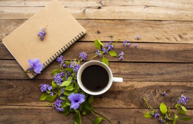 İş için dizüstü bilgisayar planlayıcısı, sıcak kahve, mor çiçek düzenleme düz arka plan ahşap üzerinde yatıyordu