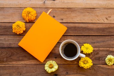 notebook planner for business work with hot coffee, flowers zinnia elegans arrangement flat lay style on background wooden