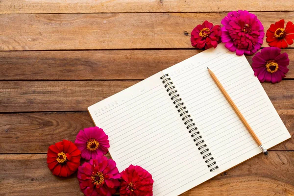 notebook planner for business work with flowers zinnia elegans arrangement flat lay style on background wooden