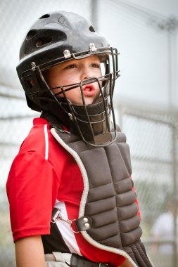 Portrait of child with catcher equipment on during baseball game clipart