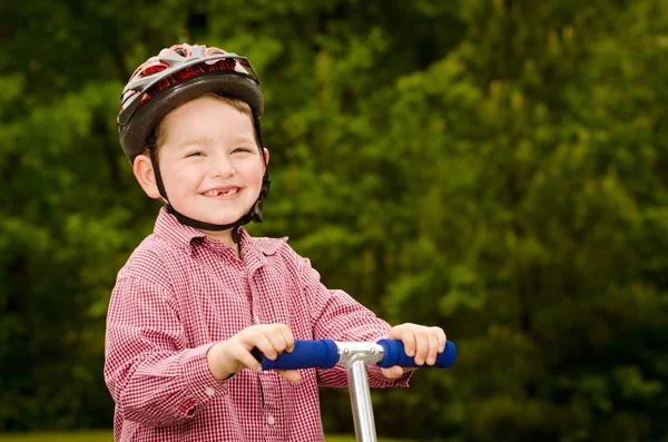 Barn med säkerhet hjälm ridning scooter utomhus — Stockfoto