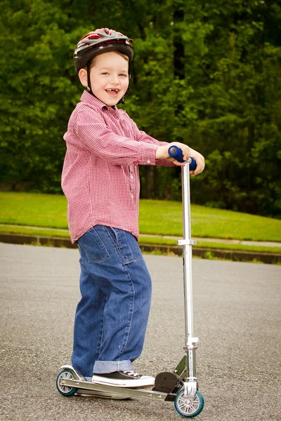 Kind met veiligheid helm paardrijden scooter buitenshuis — Stockfoto