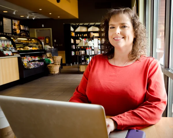 Donna che lavora al computer portatile in caffetteria — Foto Stock