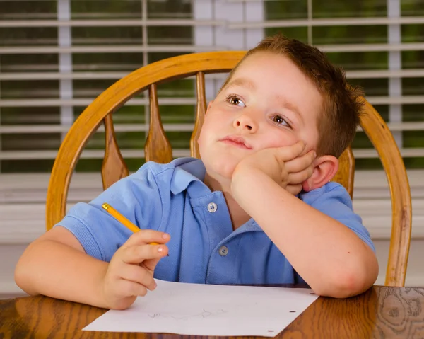 Niño reflexivo haciendo su tarea en la mesa de la cocina en casa — Foto de Stock