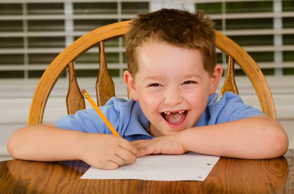 Bambino felice che fa i compiti a tavola in cucina a casa — Foto Stock