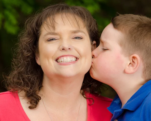 Mãe feliz rindo do beijo do filho — Fotografia de Stock