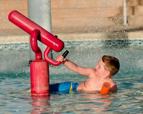 Child playing with water cannon at kiddie pool during summer — Stock Photo, Image