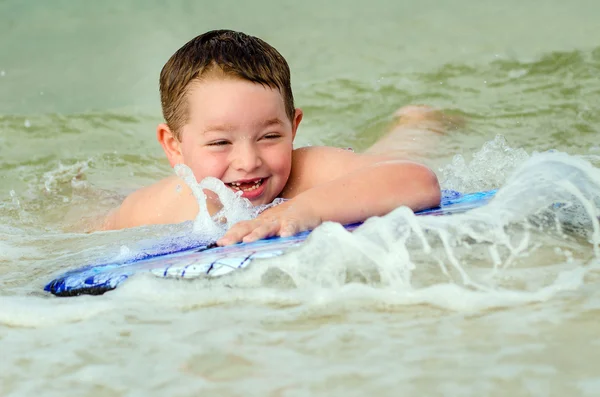 Child surfing on bodyboard at beach — Stock Photo, Image