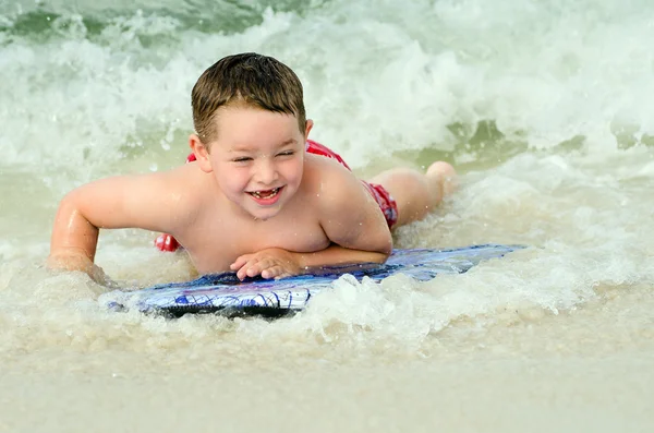 Child surfing on bodyboard at beach — Stock Photo, Image