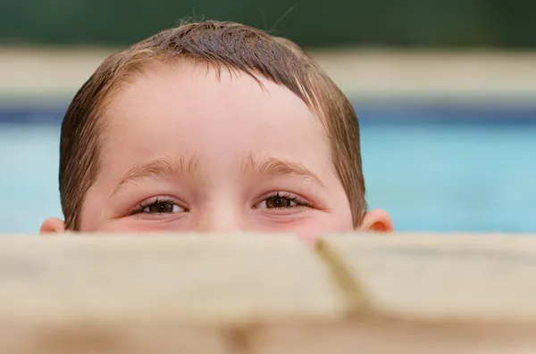 Retrato de criança espreitando sobre a borda da piscina enquanto nadava — Fotografia de Stock