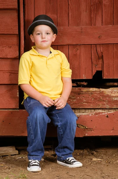 Portrait of child wearing fedora hat next to rustic barn — Stock Photo, Image