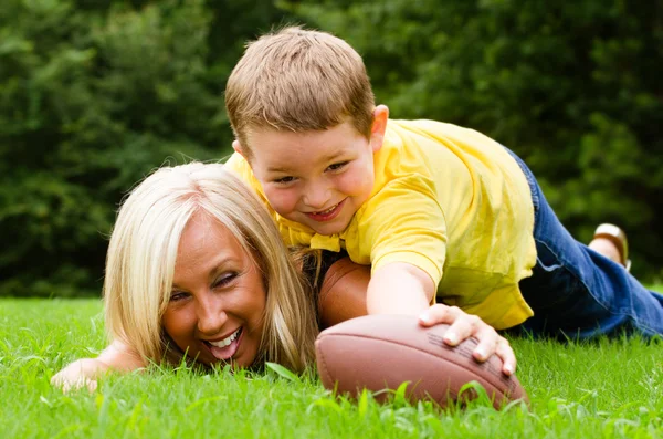 Kind aan te pakken moeder tijdens het spelen van voetbal samen buitenshuis — Stockfoto