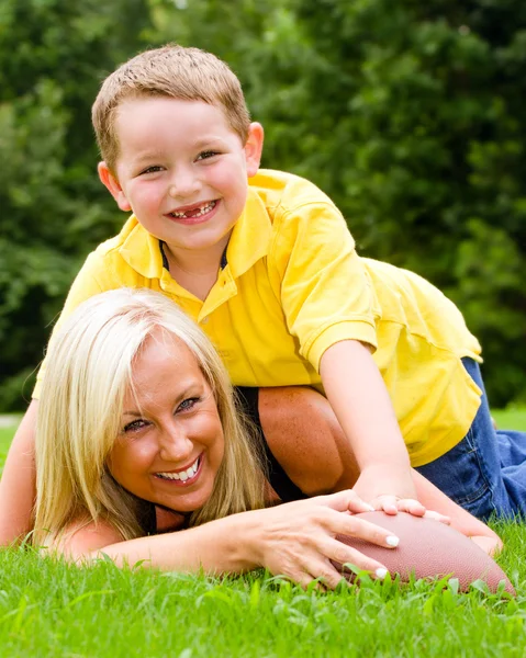 Child tackling mom while playing football together outdoors Royalty Free Stock Photos